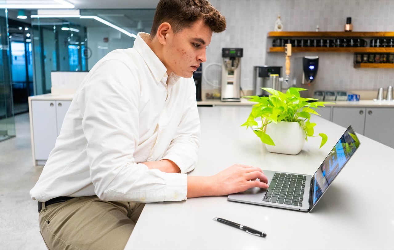 Medewerker werkt op een laptop in een licht kantoor